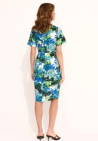Dopasowana sukienka w żywy niebieski, zielony i biały abstrakcyjny wzór. Krótkie rękawy, długość do kolan, gładki materiał i subtelne rozcięcie po bokach.