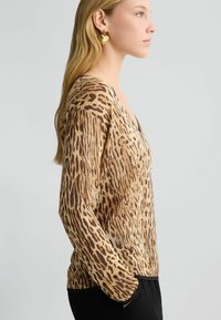 Maglione a maniche lunghe con stampa leopardata in tonalità beige e marrone, dotato di scollatura a V e polsini a coste. Tessuto a maglia texturizzata.