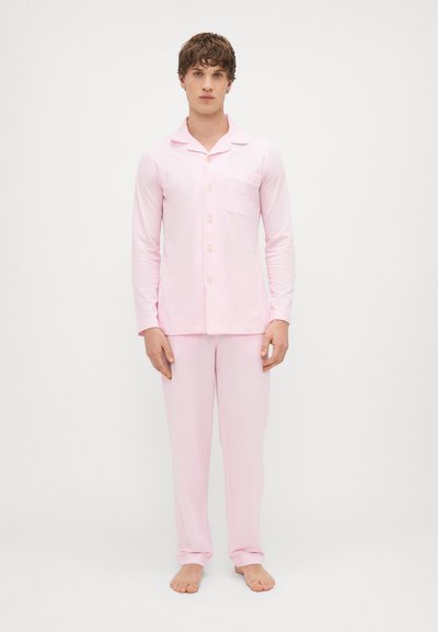 Set di pigiama rosa chiaro realizzato in tessuto morbido. Camicia a maniche lunghe con bottoni e tasca; pantaloni abbinati. Design semplice e confortevole.