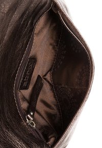 Interieur van een bruine leren handtas met een ritsvak, een soepele voering van stof en een subtiel logo-patroon aan de binnenkant.