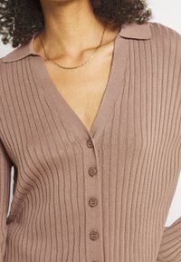 Geribbelde, mauve gebreide cardigan met een V-hals, vijf knopen aan de voorkant en een kraagontwerp met een zachte textuur.