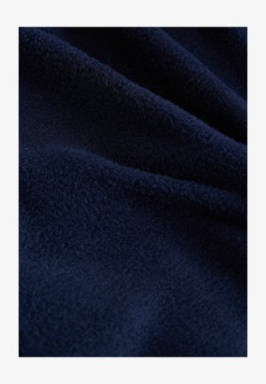 Marineblauwe fleece stof met een zachte, gestructureerde oppervlakte, die golven en plooien vertoont, geschikt voor warmte en comfort.