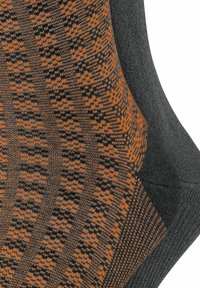 Graue Socken mit einem orange-schwarzen geometrischen Muster. Stricktextur mit geripptem Saum und glattem Fußbereich.