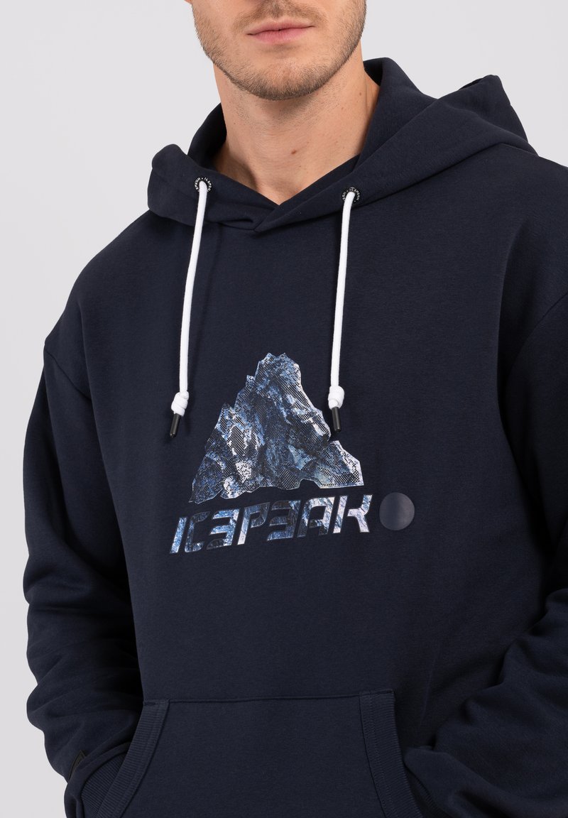 Navy Hoodie aus dickem Stoff mit Kängurutasche, versehen mit einem Bergmotiv und "ICEPEAK"-Text in metallischer Schrift. Weiße Kordeln.