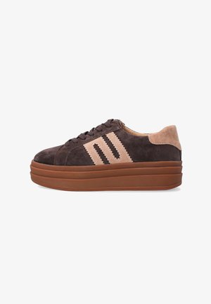 Brune suede sneakers med en tan suede hæl. Har tre diagonale striber og en struktureret brun gummisål. Snørebånd i matchende farve.