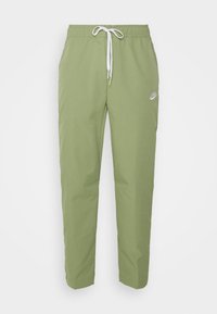 Ljusgröna Nike joggingsbyxor med elastisk midja, vit dragsko, sidofickor och liten vit Nike-logga på vänster lår.