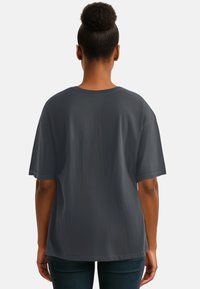 Maglietta grigia oversize con maniche corte, realizzata in tessuto morbido. Presenta un colletto tondo e una vestibilità rilassata, visibile dal retro.
