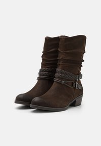 Braune Wildleder-Fußanien mit lässigem Schaft, geflochtenen Riemen und seitlichen Schnallen. Blockabsatz für mehr Höhe.