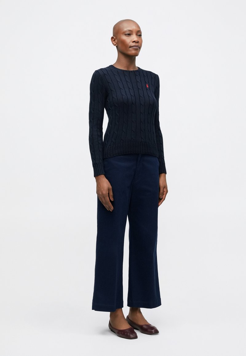 Pull en grosse maille de marine avec un col rond, associé à un pantalon large de marine et des ballerines bordeaux. Design simple, sans motifs visibles.