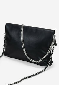 Bolso de mano de piel negra con un diseño plegado, correa de cadena plateada, textura suave y mínimos acentos de hardware.