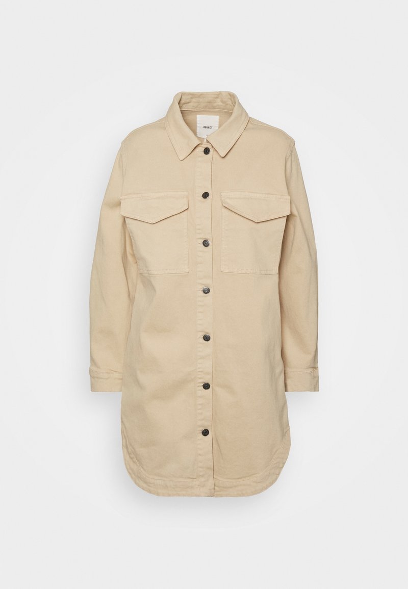 Giacca camicia beige in cotone, con colletto, due tasche sul petto, bottoni neri e maniche lunghe con orlo curvo.