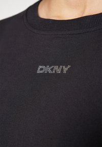 Zwarte crewneck sweatshirt van gladde stof, met een sprankelende "DKNY"-logo in rhinestones op de voorkant.