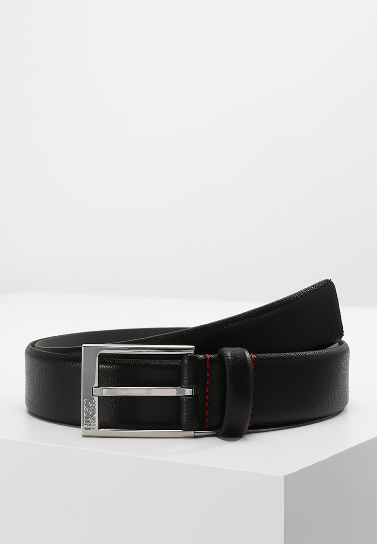 Cinturón de cuero negro con una textura suave, hebilla rectangular de plata y detalle de costura roja a lo largo del borde. Diseño plano, estética moderna.