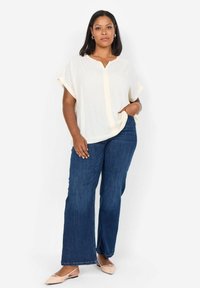 Ljus krämfärgad blus med V-hals och korta ärmar, kombinerad med mörkblå vida jeans och beige spetsiga ballerinas. Avslappnad outfit.