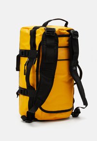 Yellow rectangular backpack with black padded shoulder straps, side compression straps, and top handle on a white background.