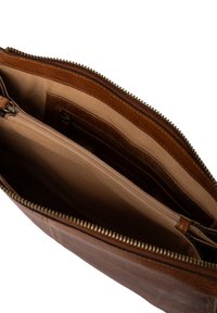 Sac en cuir marron avec fermeture éclair, présentant plusieurs compartiments intérieurs et une finition lisse et texturée. L'intérieur est de couleur beige clair.
