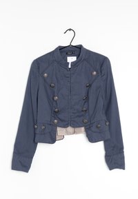 Mörkblå beskuren jacka med framträdande silverknappar, hög krage och textil med struktur. Har en figursydd design och lång ärmar.