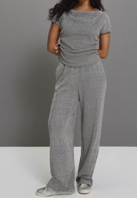 Ensemble deux pièces gris clair en tissu texturé. Haut à manches courtes avec un col rond, associé à un pantalon large et décontracté.