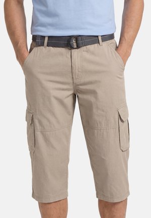 Man wearing beige knee-length cargo shorts with a black belt and hands in front pockets, shown from waist to knees.