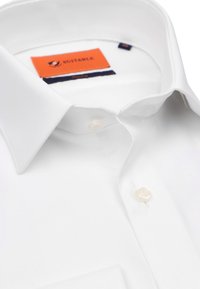 Witte overhemd met een gladde textuur, voorzien van een knoopsluiting aan de voorkant en een opvallend oranje en marineblauwe label aan de binnenkant van de kraag.