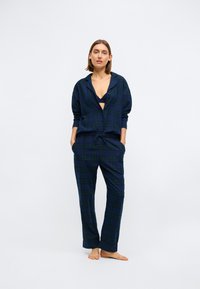 Marineblauw geruite pyjamaset met een comfortabel zittend overhemd met knopen en bijpassende broek, voorzien van groene en gele accenten en een koord in de taille.