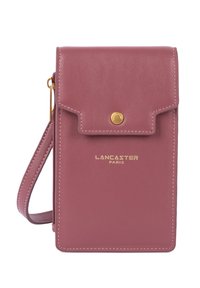 Pochette de téléphone en cuir rose avec une fermeture à rabat, des accessoires dorés et une bandoulière détachable. Présente un logo de marque embossé sur le devant.