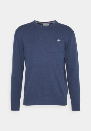 Navy blue long-sleeve sweater made of soft knit fabric. Features a round neck and a small logo on the left chest. Visible ribbed cuffs.