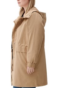Beige Außenjacke mit Kapuze, Frontreißverschluss und Druckknopfverschluss, mit elastischen Bündchen und zwei Seitentaschen.