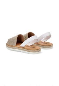 Parte superior de yute tejido en color beige con dos tiras blancas, plantilla en tono marrón y suela de yute texturizada. Diseño plano adecuado para uso casual.