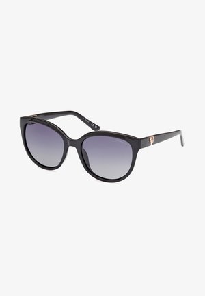 Ochelari de soare din plastic negru, cu o formă supradimensionată de tip cat-eye și lentile gri cu gradient. Prezintă un branding subtil de ton auriu pe templu.