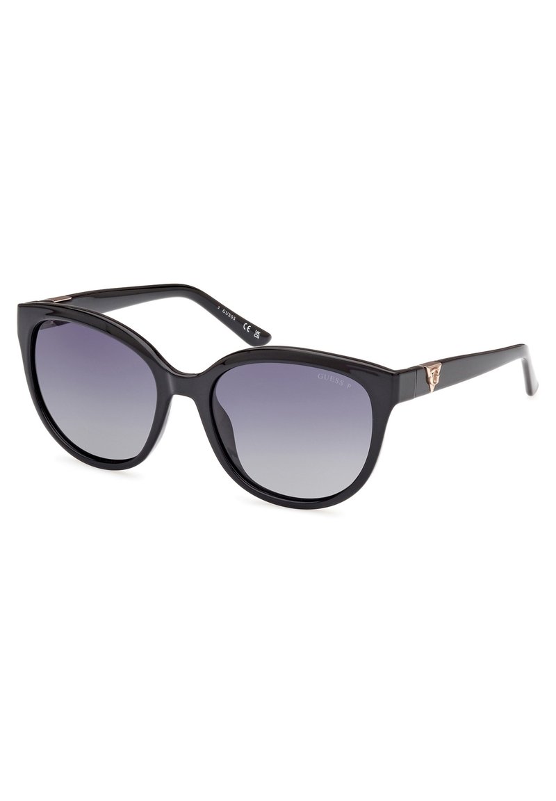 Zwarte plastic zonnebril met een oversized cat-eye vorm en gradient grijze lenzen. Bevat subtiele goudkleurige branding op de tempel.