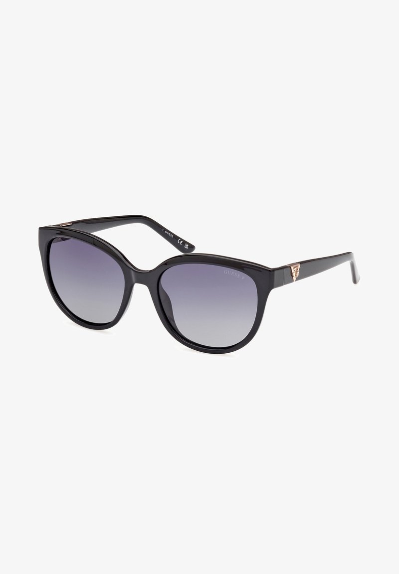 Zwarte plastic zonnebril met een oversized cat-eye vorm en gradient grijze lenzen. Bevat subtiele goudkleurige branding op de tempel.