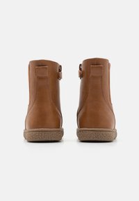 Brune lær ankle støvler med rund tå, teksturert gummisåle, og sidehanker for enkel påkledning. Glatt overflate med sømdetaljer.