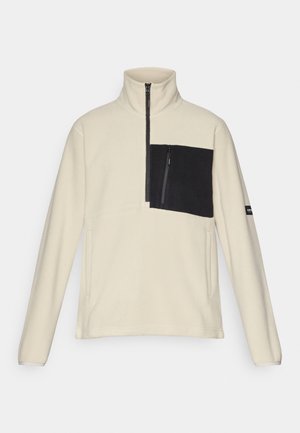 Fliisitakki vaaleassa sävyssä, jossa musta rintaosa. Varusteena korkea kaulus, vetoketjukiinnitys ja sivutaskut. Pehmeä rakenne, rento muotoilu.