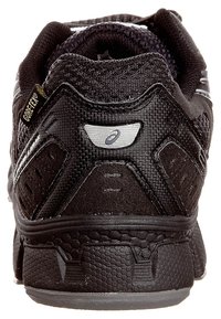 Chaussure de sport noire avec une tige en mesh texturé, un talon renforcé, des accents réfléchissants et une semelle extérieure en caoutchouc avec un motif hexagonal.