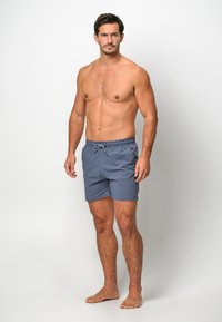 Shorts de bain pour hommes en tissu bleu marine, dotés d'une taille élastique avec cordon de serrage, d'une longueur au-dessus du genou et d'une texture lisse.