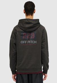 Ciemnoszara bluza z kapturem z dużym graficznym nadrukiem przedstawiającym "223" i "OFF PITCH" na plecach. Miękka tkanina, luźny krój i kieszeń kangurza.