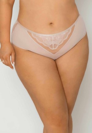 Kobieta plus size w cielistych majtkach z kwiatowym haftem z siateczki z przodu, stojąca na jasnym, jednolitym tle.