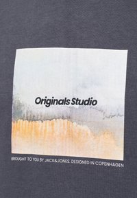 T-shirt grigia con una stampa rettangolare in acquerello dai colori tenui, testo "Originals Studio" e "Portato a te da JACK&JONES."