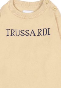 Pull beige avec un col en tricot côtelé et des accents de boutons. "TRUSSARDI" est brodé en bleu marine sur le devant. Texture douce.