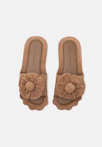 Paire de sandales marron à enfiler avec une grande décoration florale en tissu et des bords festonnés, nom de marque Marc Jacobs visible sur les semelles intérieures.