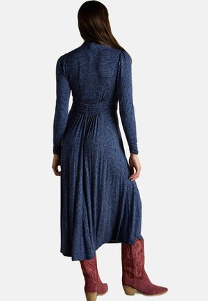Navy blue, long-sleeved dress with floral pattern, cinched waist, and pleated skirt. Worn with pink cowboy boots featuring embroidered details.