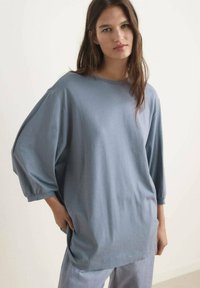 Ljusblå oversized t-shirt i mjukt material, med rund halsringning och lösa trekvartsärmar med elastiska manchetter.