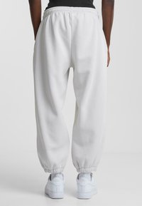 Hvide sweatpants med elastisk talje og manchetter, lavet af blødt stof. Kombinationen med hvide sneakers skaber fokus på en afslappet pasform.