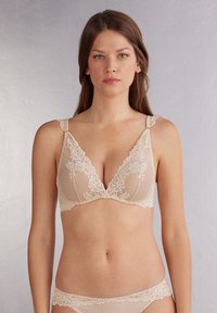 Béžová krajková trojúhelníková podprsenka s květinovými vzory, nastavitelné ramínka a strukturovaný síťovaný design. Sada kalhotek se krajkovými akcenty.