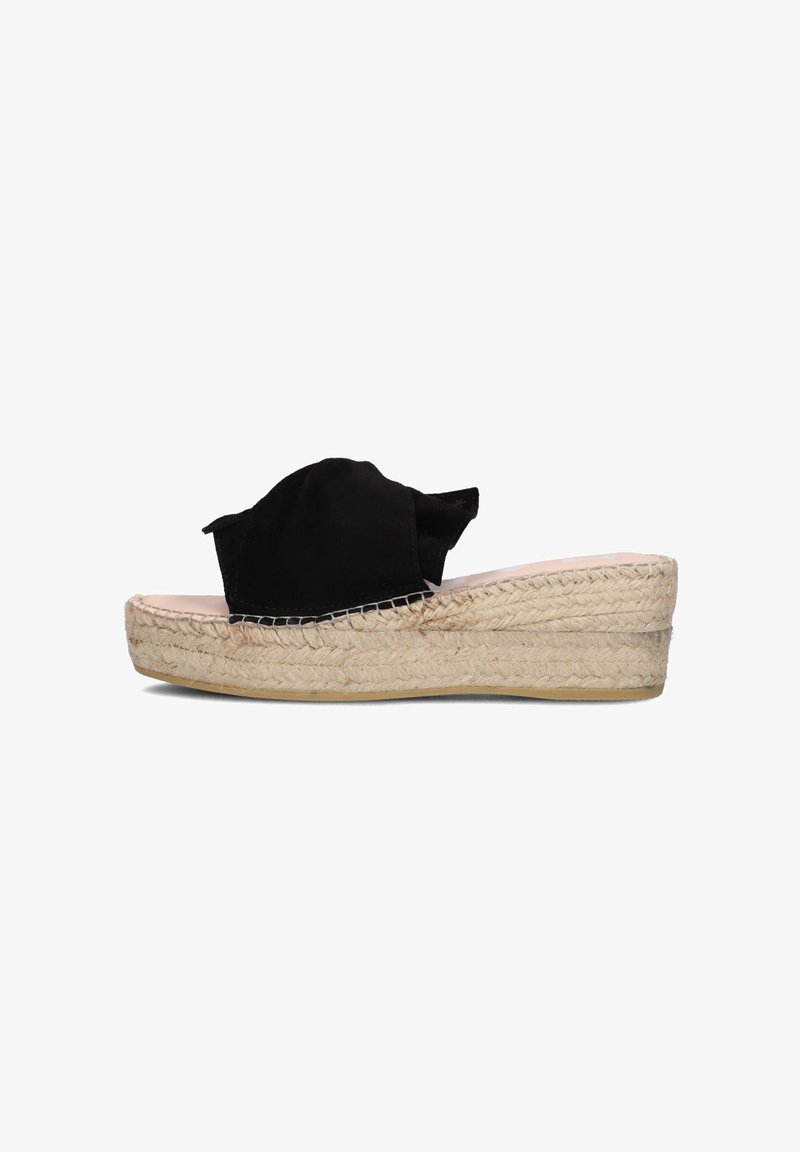 Zwarte suède espadrille-slipper met een brede, ronde bovenkant en een beige geweven jute platform. Heeft een gestructureerde zool en minimale ontwerpelementen.