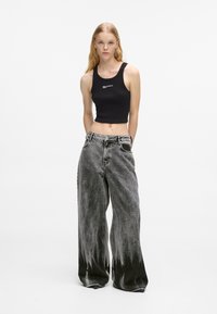 Black ribbed crop top paired with oversized, acid-wash grey jeans featuring a subtle fade and front pockets.