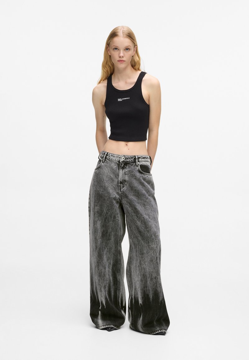 Black ribbed crop top paired with oversized, acid-wash grey jeans featuring a subtle fade and front pockets.