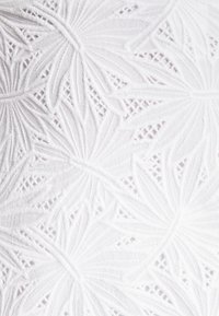 Tissu blanc avec des broderies florales complexes, présentant des lignes en relief et texturées ainsi que des motifs découpés. Éléments de design détaillés et délicats.