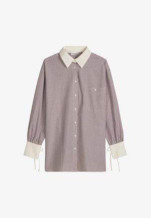 Chemise à manches longues à boutons avec de fines rayures verticales rouges, col pointu blanc, larges poignets blancs avec liens, et une poche poitrine.